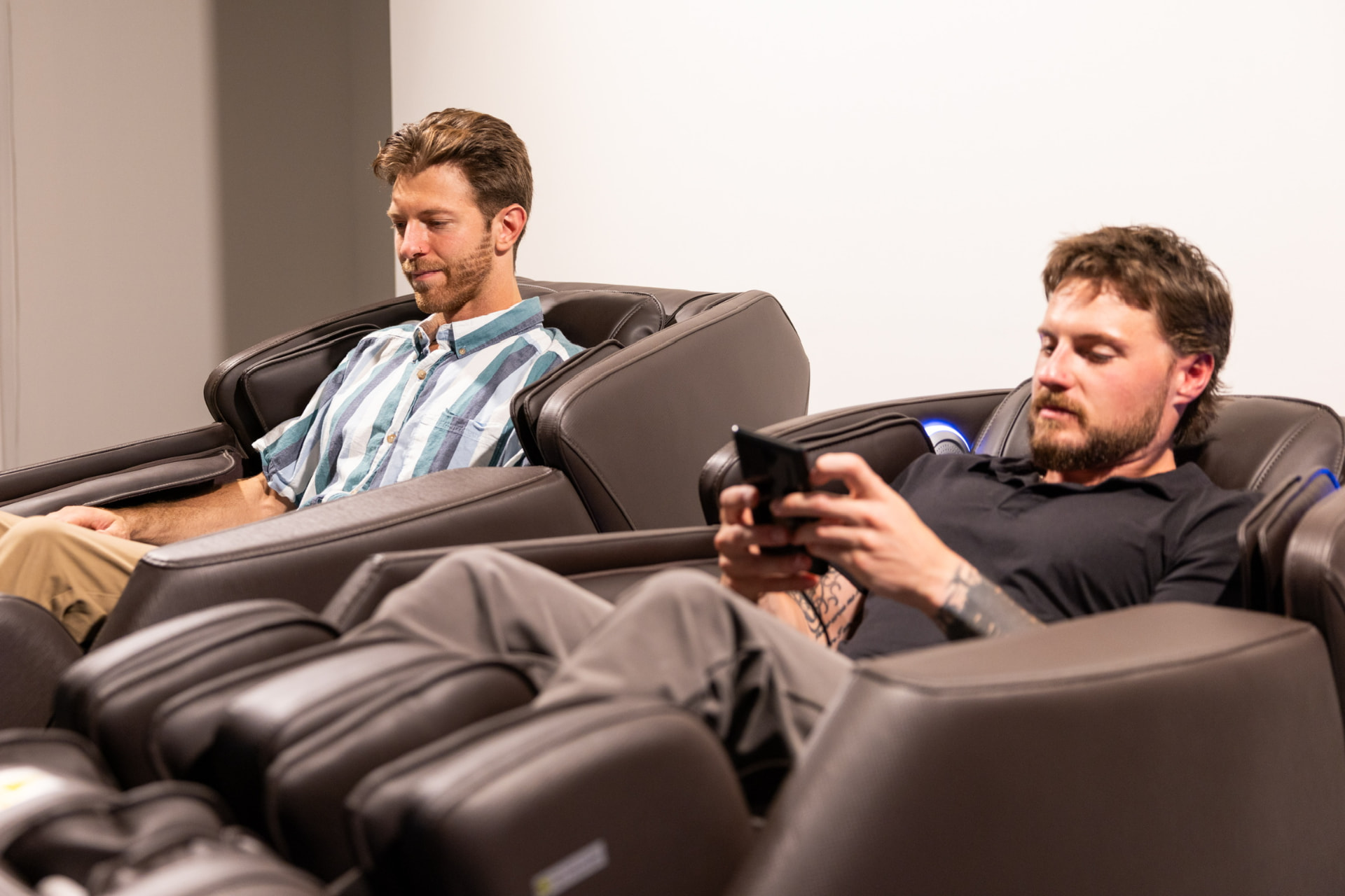 Two men unwinding side by side in massage chairs during a workplace wellness break