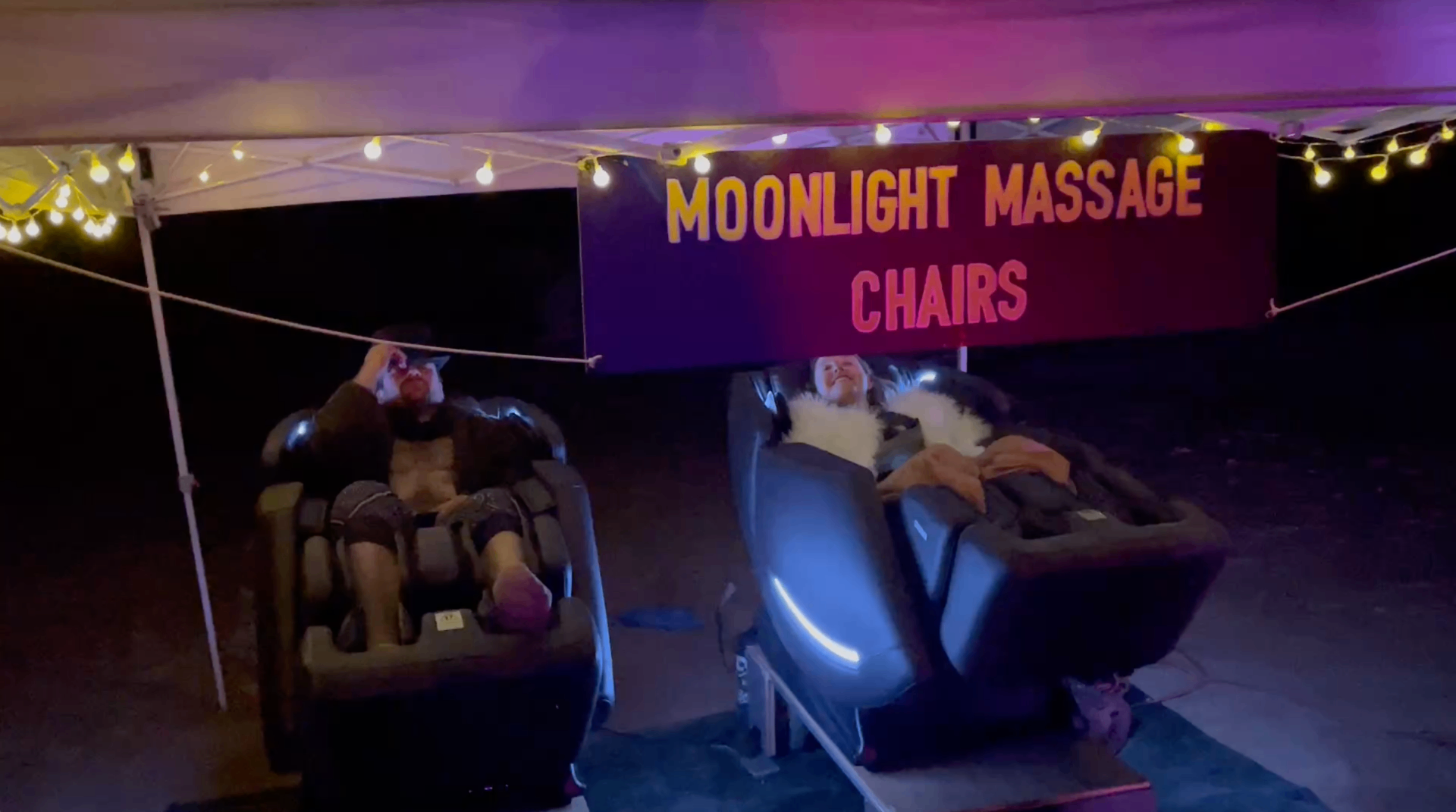 Two guests relaxing in Moonlight Massage Chairs at night under glowing string lights