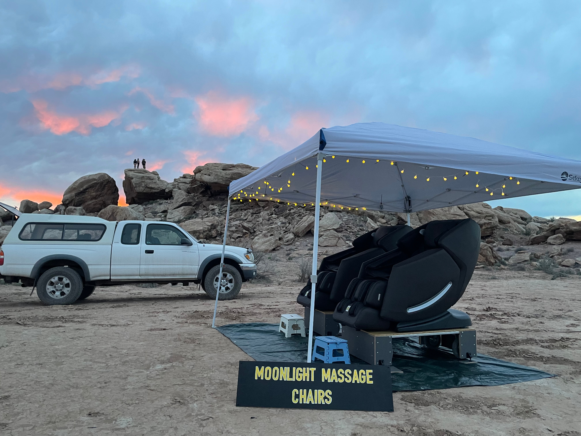 Moonlight Massage Chairs canopy setup at a desert sunset with string lights